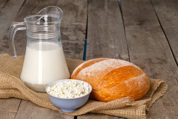Glazen pot melk, kom kwark en brood op houten tafel — Stockfoto