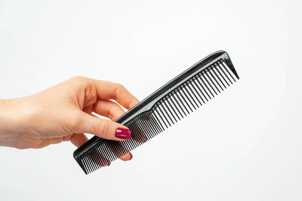 Female hand holding hair comb against white background — Stock Photo, Image