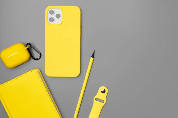 Sarı not defteri, akıllı telefon ve gri arka planda kulaklık. — Stok fotoğraf