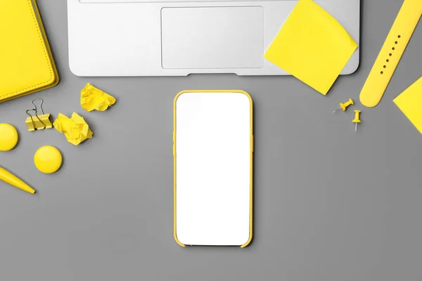 Gele notitieblok met smartphone en pen op grijze achtergrond — Stockfoto