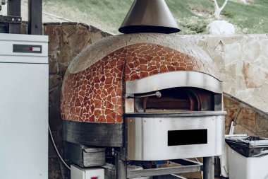 Bir restoranda mozaik dekorasyonu olan açık hava pizza fırını.