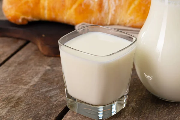 Egy csésze tej és kenyérpirítós a fa asztalon. — Stock Fotó