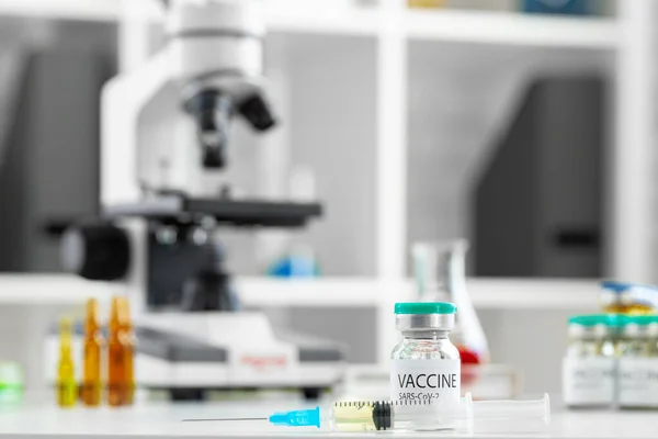 실험실 배경에서 탁자 위에 주사용 유리병에 주사하는 백신 — 스톡 사진
