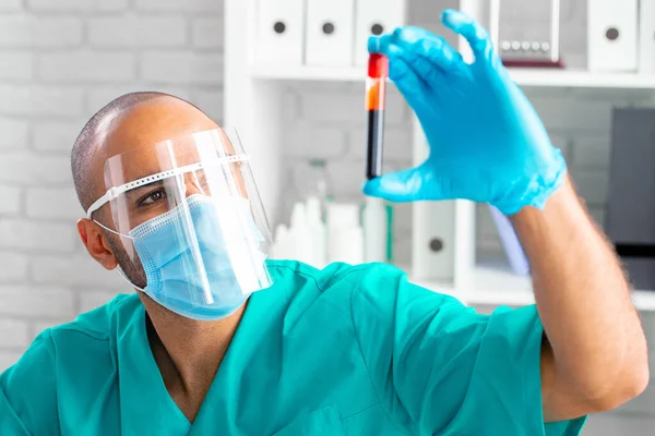 African american doctor or laboratory worker examines blood sample in clinic — Stock Photo, Image