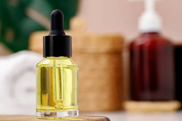 Bottle of yellow cosmetic oil on wooden tray close up