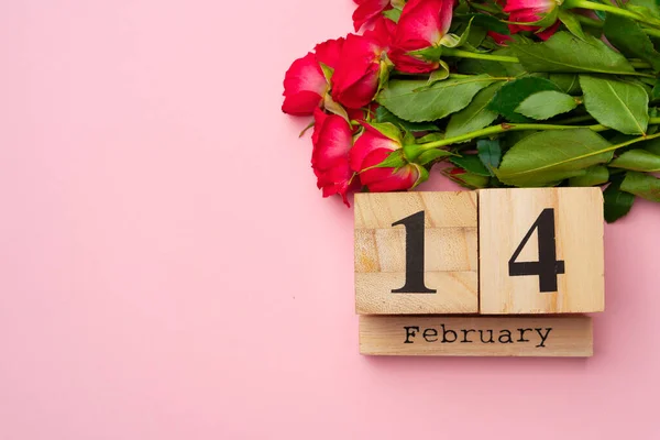 Calendario in legno 14 febbraio e rose su sfondo rosa — Foto Stock