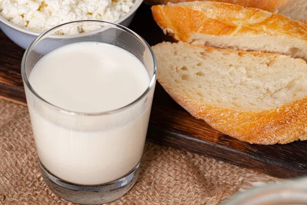 Egy pohár tej, egy tál túró és kenyér az asztalon. — Stock Fotó