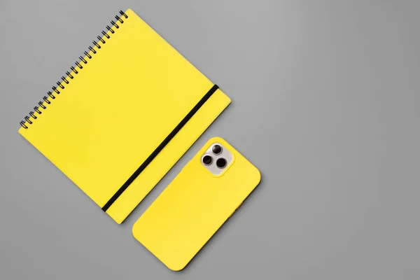 Carnet jaune et smartphone sur fond gris — Photo