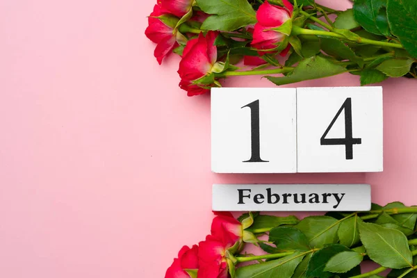 Calendario in legno 14 febbraio e rose su sfondo rosa — Foto Stock