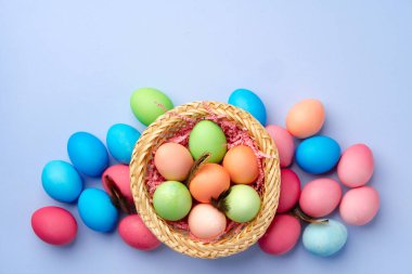 Mavi arka planda dekoratif yuvada renkli Paskalya yumurtaları