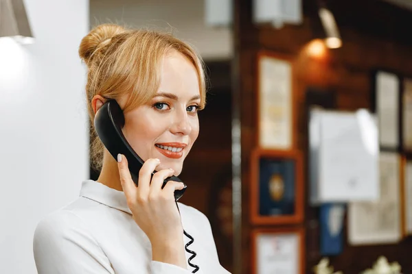Boa aparência amigável mulher recepcionista do hotel falando ao telefone — Fotografia de Stock