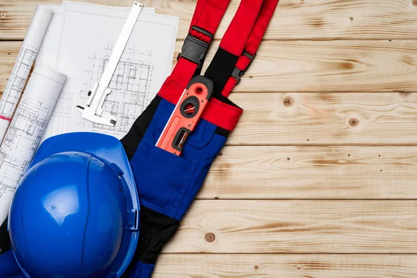 Byggnadsarbetare unifrån, hatt och ritningar på trä bakgrund — Stockfoto