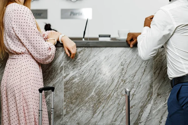 Oigenkännlig man och kvinna med resväskor står nära receptionen på hotellet — Stockfoto