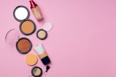 Pembe arka planda yüz rengi için kozmetik ürünler