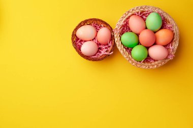Sarı arka planda renkli Paskalya yumurtaları olan dekoratif bir yuva.