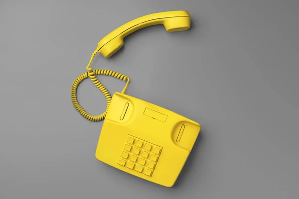 Telefono fisso giallo su sfondo grigio vista dall'alto — Foto Stock
