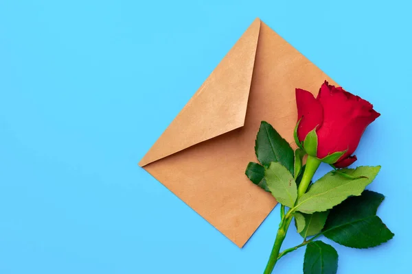 Червона троянда з конвертом на синьому фоні зверху — стокове фото