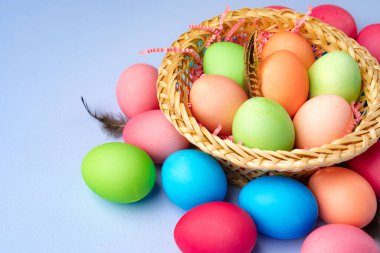 Mavi arka planda dekoratif yuvada renkli Paskalya yumurtaları