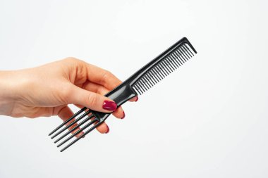 Beyaz arka planda saç tarağı tutan kadın.