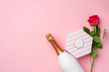 Rose, hediye kutusu ve pembe arka planda bir şişe şampanya.