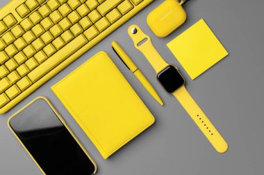 Akıllı telefon, akıllı seğirme ve gri arka planda kulaklık olan sarı not defteri.