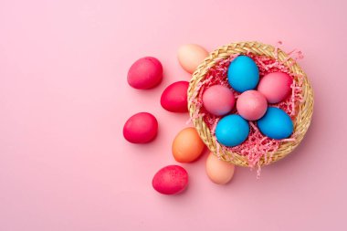 Pembe arka planda dekoratif yuvada boyanmış Paskalya yumurtaları