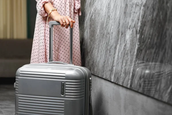 Unerkennbare Frau in rosa Kleid steht mit Koffer — Stockfoto