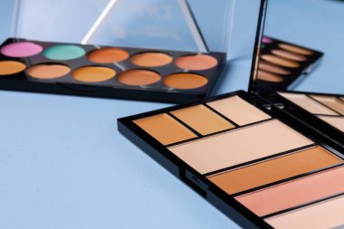 Cilt makyaj ürünleri ve mavi arkaplanda fırça