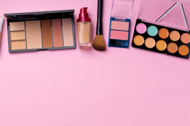Cilt makyaj ürünleri ve pembe arka planda fırça