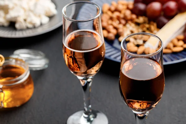 Szklanka wina i talerz z orzechami na czarnym stole — Zdjęcie stockowe