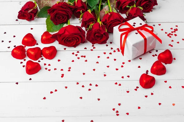 Ημέρα του Αγίου Βαλεντίνου. Κόκκινα τριαντάφυλλα και κουτί δώρου σε ξύλινο τραπέζι — Φωτογραφία Αρχείου