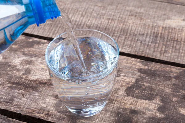 Un vaso de agua sobre una mesa de madera — Foto de Stock