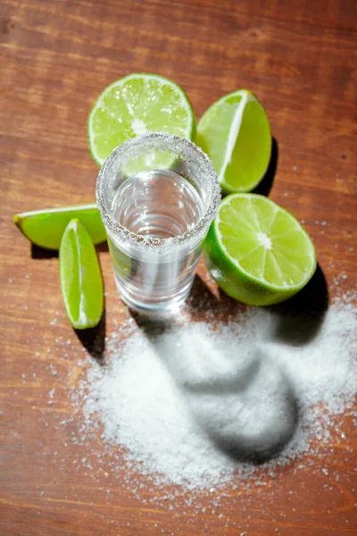 Tequila disparos de plata con rodajas de lima y sal sobre tabla de madera —  Fotos de Stock