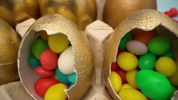Gyllene dekorativa påskägg fyllda med färgglada godis på träbord på nära håll — Stockvideo
