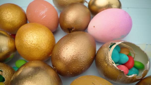 Easter eggs painted in gold color on blue wooden table close up — Stock Video