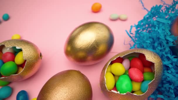 Χρυσά αυγά με διάσπαρτα γλυκά για το Πάσχα σε ροζ φόντο — Αρχείο Βίντεο