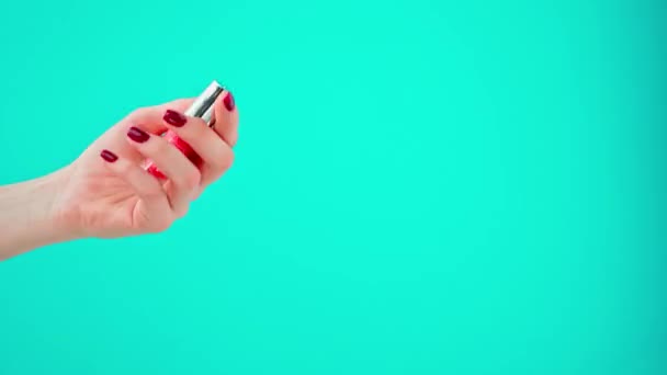 Kvinna hand hålla flaska nagellack mot blå bakgrund — Stockvideo