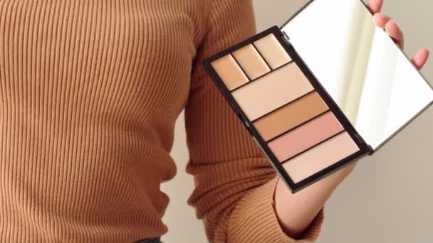 Mains féminines présentant la palette de maquillage avec fond de teint — Video