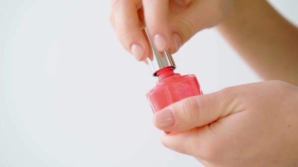 Female hand holding nail polish bottle against white background — Stock Video