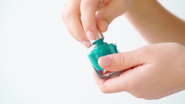 Vrouwelijke hand houden nagellak fles tegen witte achtergrond — Stockvideo