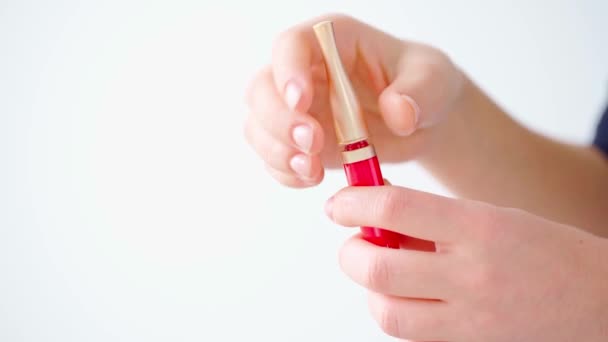Tangan wanita memegang lip gloss terhadap latar belakang putih — Stok Video