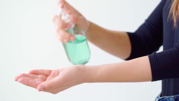 Женщина применяет гель для дезинфекции рук на белом фоне — стоковое видео