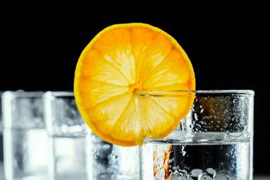 Siyah arka planda shot bardaklarında soğuk votka..