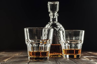 Eski ahşap masada viski bardağı ve şişe.