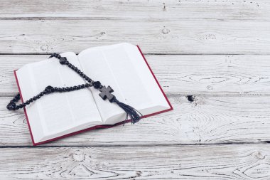 İncil ve beyaz tahta bir masanın üzerindeki haç..