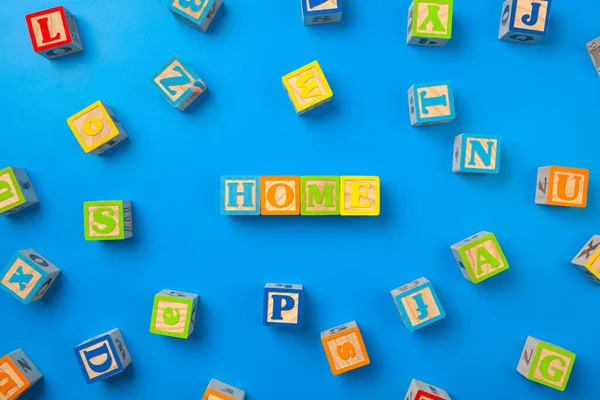 À la maison. Blocs d'alphabet colorés en bois sur fond bleu, plan, vue de dessus. — Photo