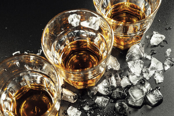 Whiskey and ice on rustic wood background