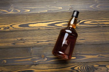 Viski şişesi koyu ahşap arka planda düz yatıyordu.