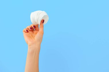 Mavi arka planda pamuk diskleri tutan kadın.