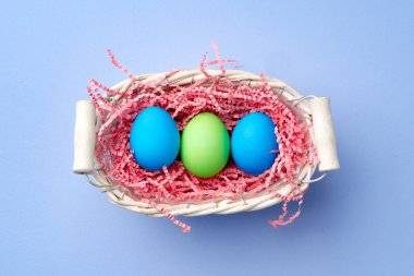 Mavi arka planda dekoratif yuvada renkli Paskalya yumurtaları